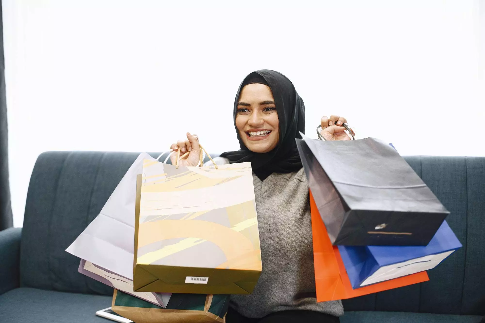 Arabic woman in headscarf sitting on a sofa with packages. Girl did online shopping