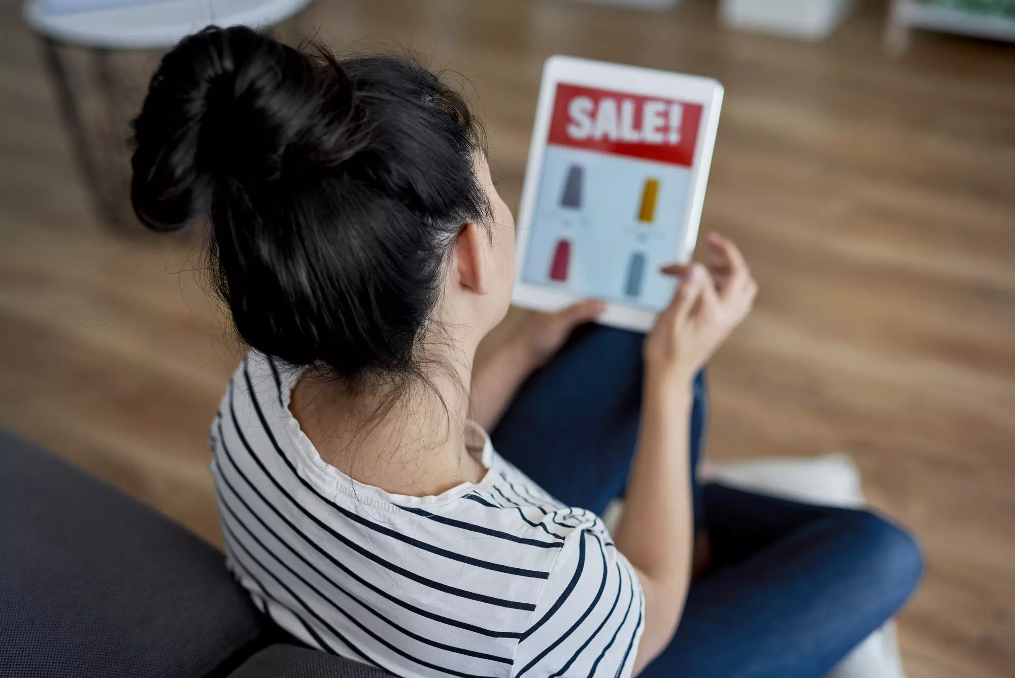 Rear view of young woman watching sales on the tablet.